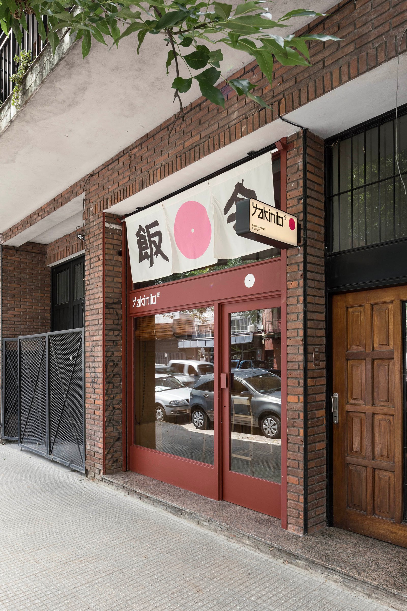 Fachada de restaurante japonés con cartel y detalles rojos — proyecto Yakinilo, por Estudio YME, en Av. Dorrego 1551